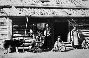 Фотография семьи на фоне деревянного дома